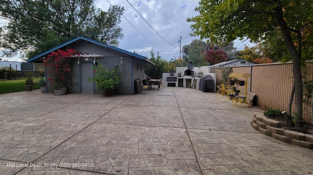 view of side of property with a patio area, fence, and an outdoor structure