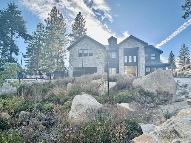 view of front of house featuring metal roof, stone siding, and a standing seam roof