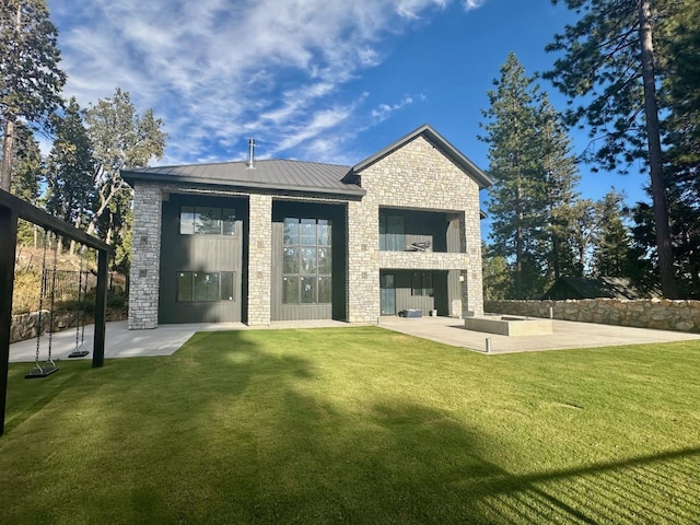 back of property featuring metal roof, fence, stone siding, a yard, and a patio area