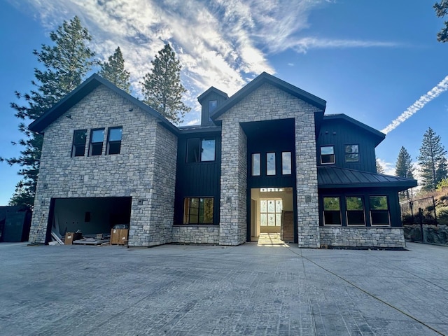 view of front of house featuring an attached garage, a standing seam roof, metal roof, and board and batten siding