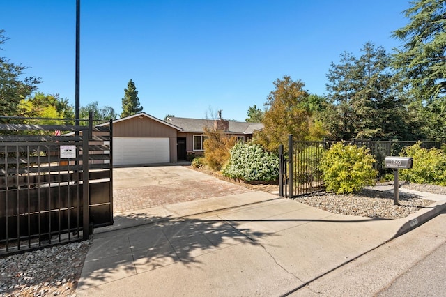 view of front of house featuring driveway, an attached garage, fence, and a gate