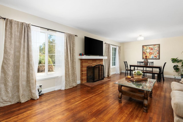 living room with a brick fireplace, wood finished floors, and baseboards