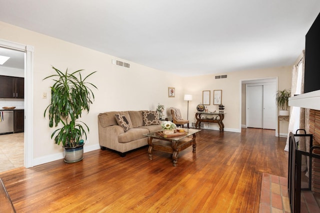 living area with light wood-style floors, baseboards, a fireplace, and visible vents