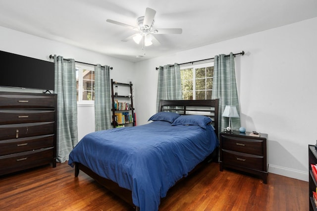 bedroom with multiple windows, wood finished floors, and baseboards