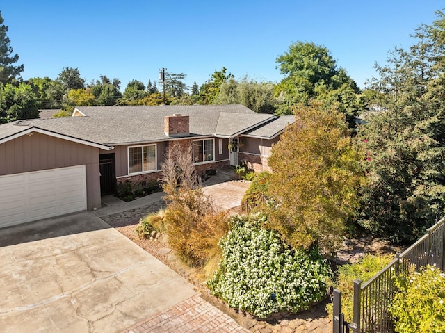 single story home featuring a garage, concrete driveway, a chimney, roof with shingles, and fence