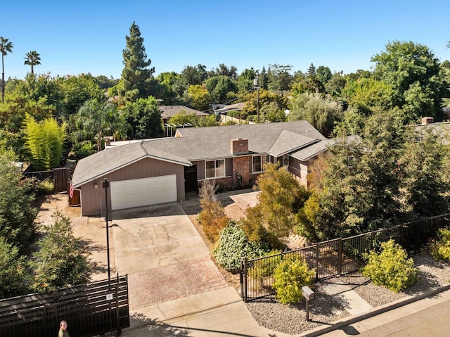 ranch-style house with a garage, concrete driveway, a chimney, and fence