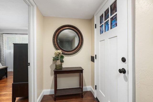 doorway featuring baseboards and wood finished floors