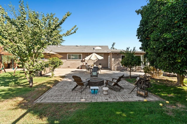 back of property featuring a yard, an outdoor fire pit, a patio area, and stucco siding