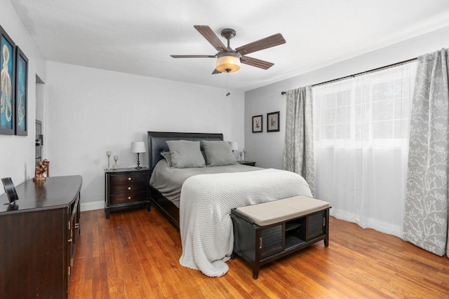 bedroom with wood finished floors, a ceiling fan, and baseboards