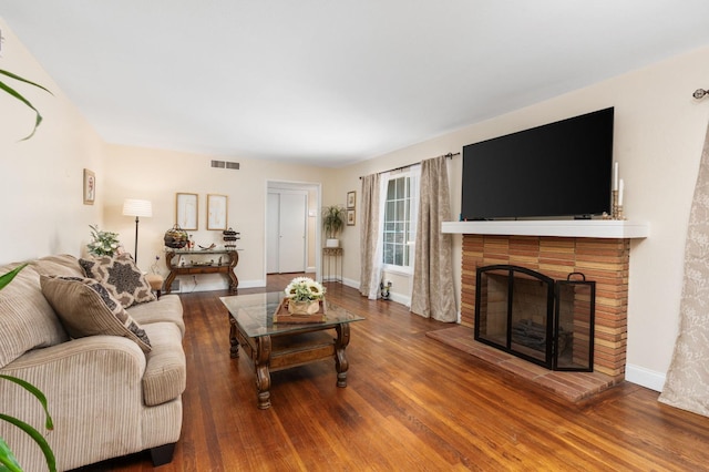 living area featuring visible vents, a fireplace, baseboards, and wood finished floors