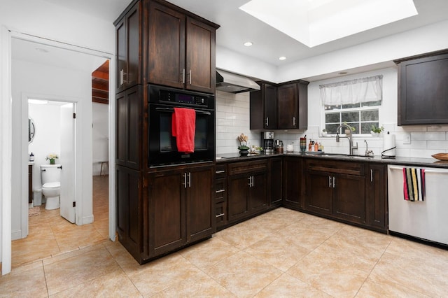 kitchen featuring under cabinet range hood, a sink, black oven, stainless steel dishwasher, and dark countertops