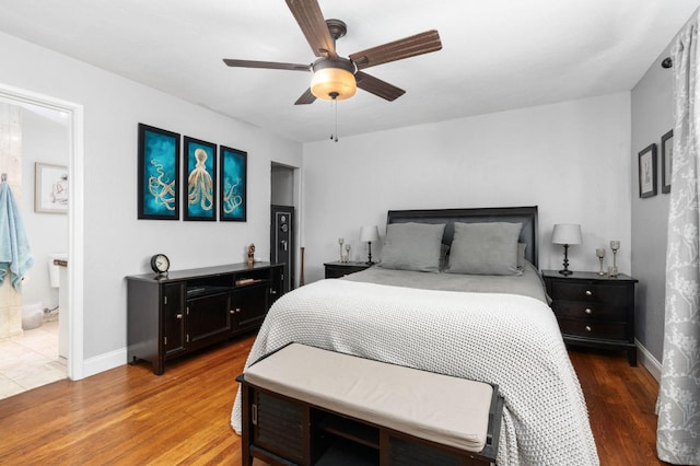 bedroom featuring a ceiling fan, baseboards, wood finished floors, and ensuite bathroom