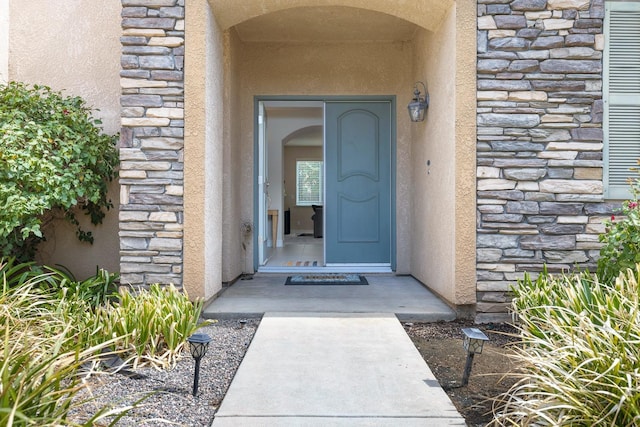 doorway to property with stone siding and stucco siding