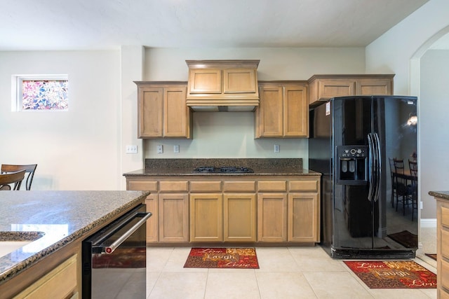 kitchen with dark stone countertops, gas stovetop, black fridge with ice dispenser, and dishwasher