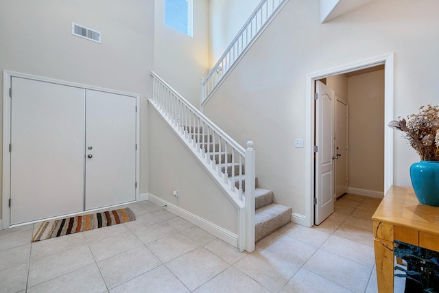 entryway with tile patterned floors, visible vents, baseboards, and stairs