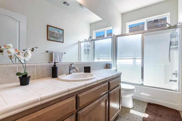 bathroom featuring toilet, vanity, visible vents, and enclosed tub / shower combo