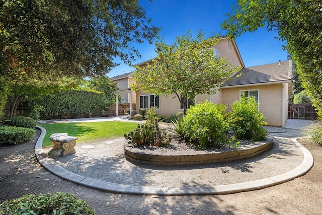 rear view of house with a lawn, a patio, a tile roof, fence, and stucco siding