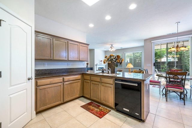 kitchen featuring black dishwasher, light tile patterned floors, a sink, a peninsula, and ceiling fan with notable chandelier