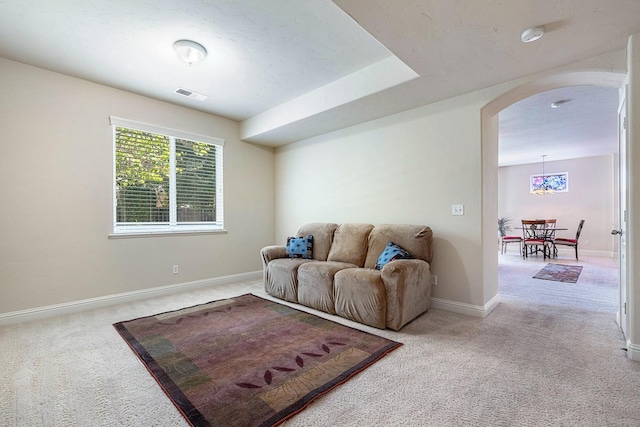 living area featuring carpet floors, baseboards, visible vents, and arched walkways