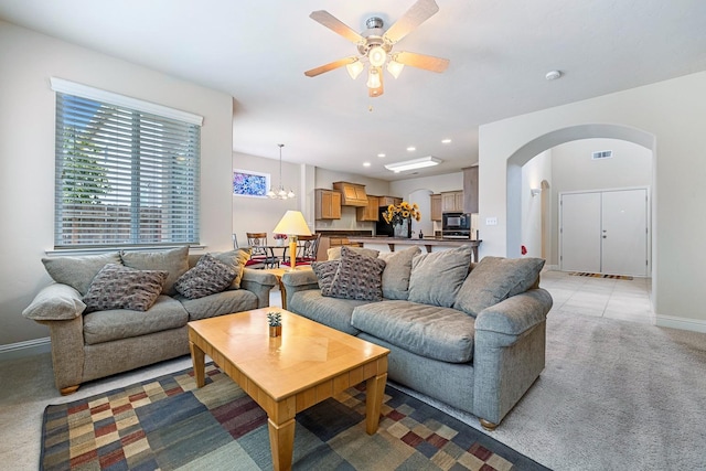 living area featuring visible vents, arched walkways, baseboards, light colored carpet, and recessed lighting