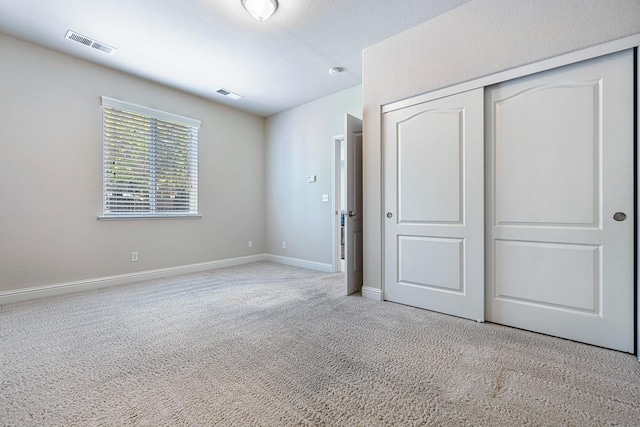 unfurnished bedroom with baseboards, a closet, visible vents, and light colored carpet