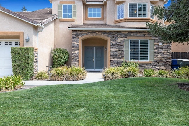 property entrance featuring an attached garage, a tiled roof, stone siding, a lawn, and stucco siding