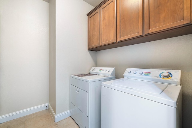 laundry room with cabinet space, light tile patterned floors, baseboards, and washer and clothes dryer