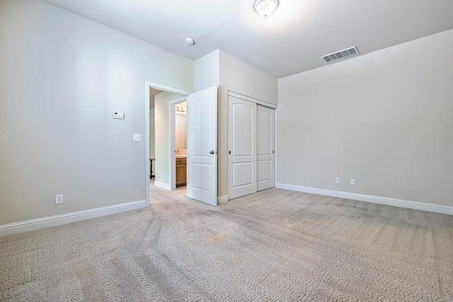 unfurnished bedroom featuring baseboards, visible vents, a closet, and light colored carpet