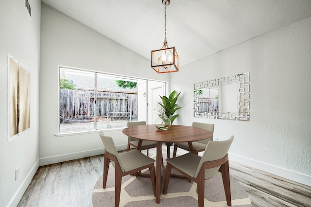 dining area featuring visible vents, vaulted ceiling, wood finished floors, a chandelier, and baseboards