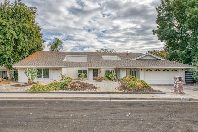 view of front of property featuring driveway, a garage, and roof with shingles