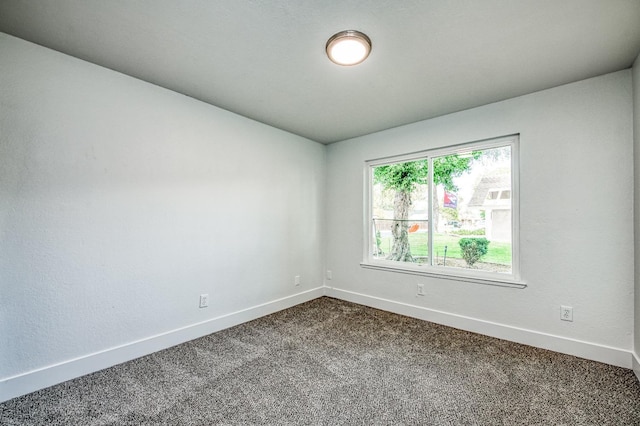 unfurnished room featuring dark carpet and baseboards