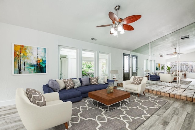 living room featuring lofted ceiling, a ceiling fan, visible vents, and wood finished floors