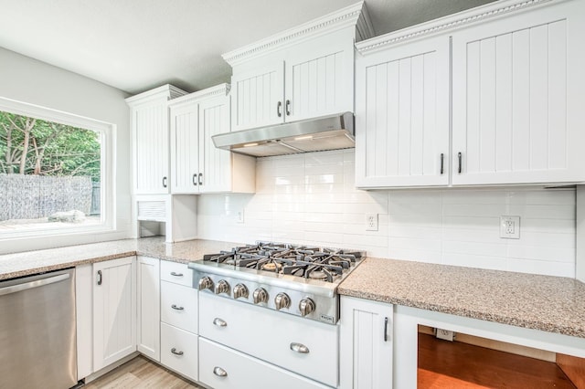 kitchen featuring light stone counters, stainless steel appliances, tasteful backsplash, white cabinetry, and under cabinet range hood