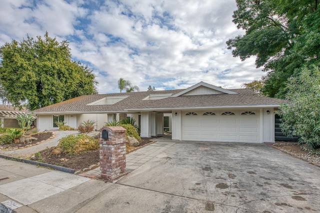 ranch-style home featuring concrete driveway, a shingled roof, and an attached garage