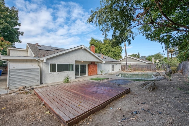 back of property featuring solar panels, a fenced backyard, a deck, and stucco siding