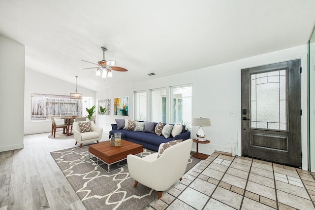 living area with baseboards, visible vents, a ceiling fan, vaulted ceiling, and light wood-type flooring