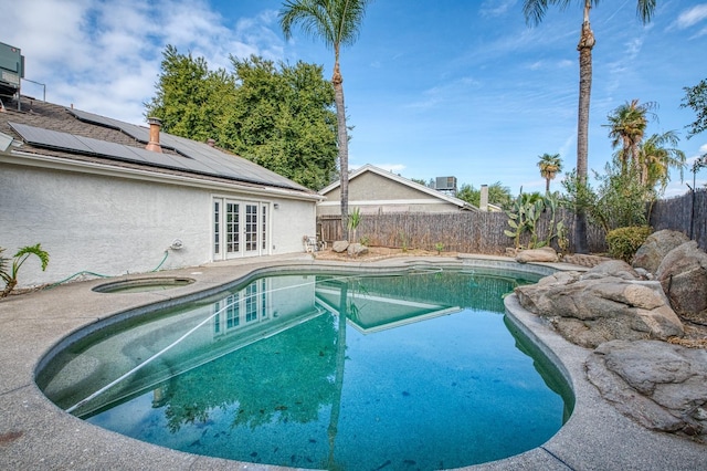 view of swimming pool featuring a patio, a fenced backyard, an in ground hot tub, french doors, and a fenced in pool