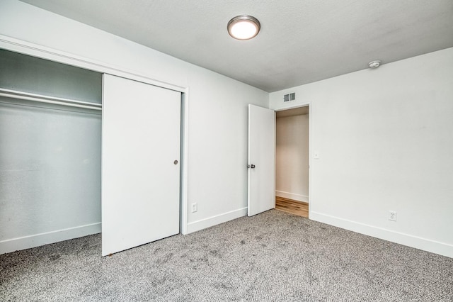 unfurnished bedroom featuring a closet, carpet flooring, visible vents, and baseboards