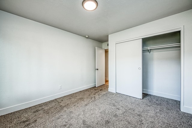 unfurnished bedroom featuring a closet, baseboards, and carpet flooring