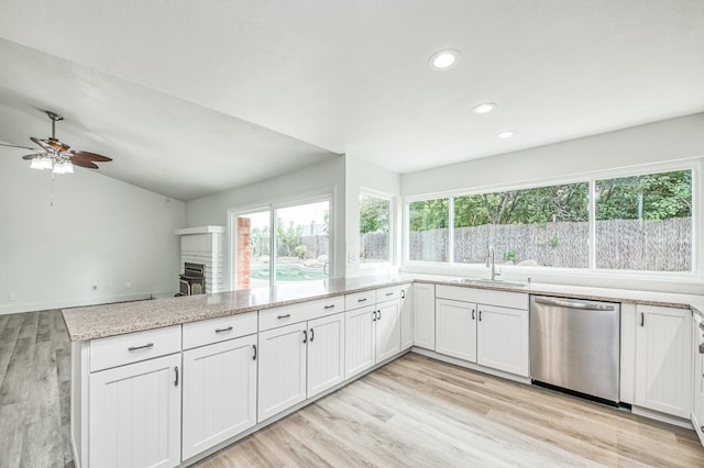 kitchen with a peninsula, a sink, light wood-style floors, vaulted ceiling, and stainless steel dishwasher