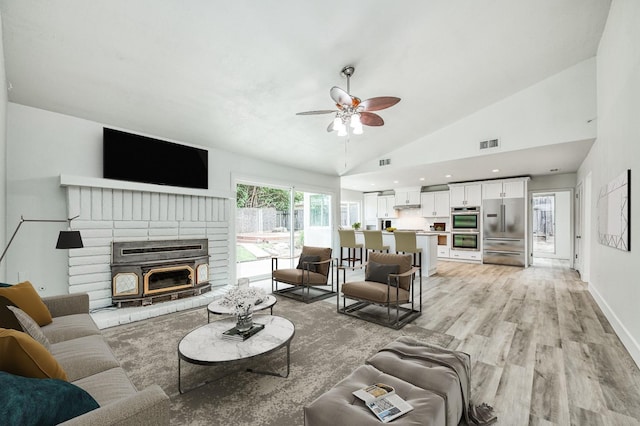 living area with visible vents, light wood-style floors, ceiling fan, high vaulted ceiling, and baseboards