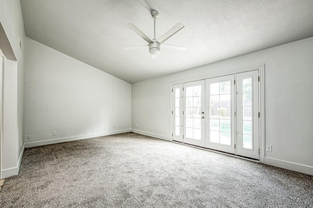 carpeted spare room featuring baseboards, ceiling fan, vaulted ceiling, a textured ceiling, and french doors