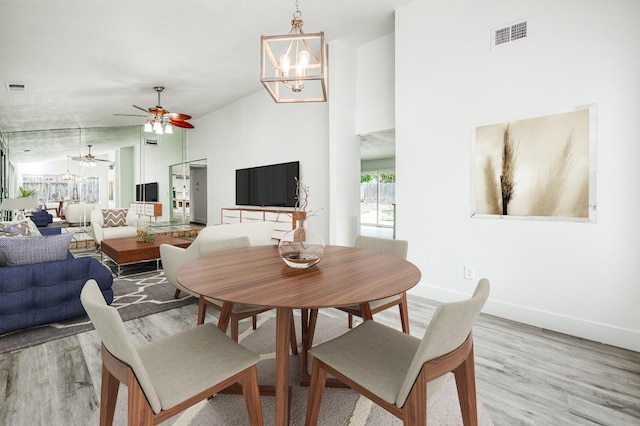 dining space with baseboards, ceiling fan with notable chandelier, visible vents, and light wood-style floors