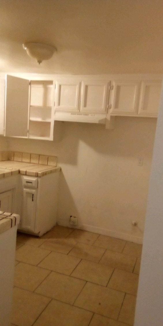 kitchen featuring white cabinetry and tile countertops
