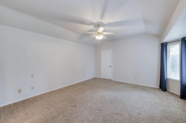 empty room with vaulted ceiling, baseboards, a ceiling fan, and light colored carpet