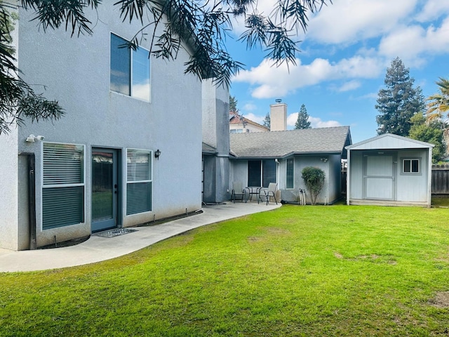 rear view of house with an outbuilding, stucco siding, a lawn, a patio area, and a shed