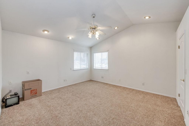 carpeted spare room featuring ceiling fan, baseboards, and vaulted ceiling