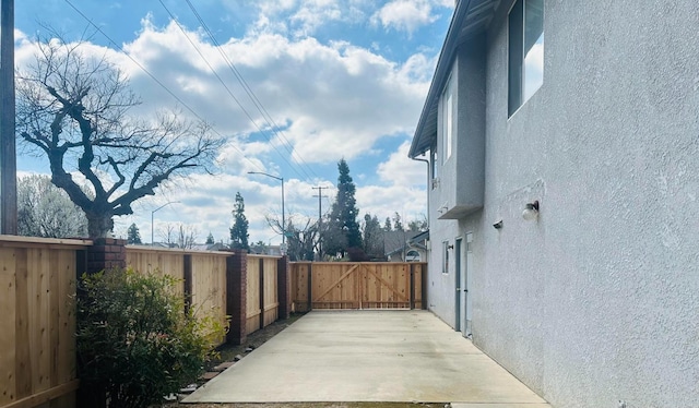 view of side of home featuring a gate, fence, and stucco siding