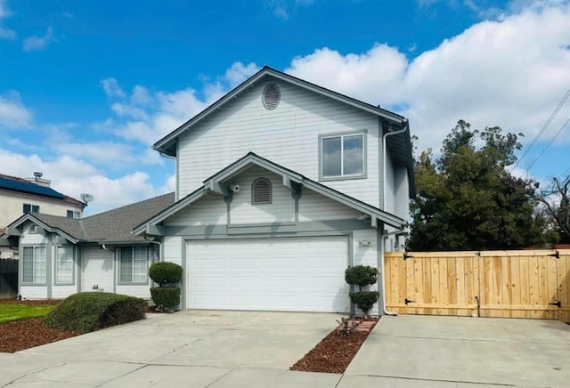 view of front facade featuring concrete driveway, fence, and a gate