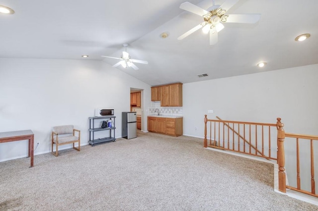 interior space featuring lofted ceiling, light carpet, an upstairs landing, visible vents, and a ceiling fan